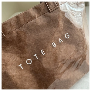 Detail view of the waterproof PVC layer and textured brown fabric with TOTE BAG print