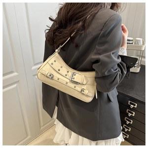 Close-up of cream shoulder bag featuring punk metallic buckles and rivet details