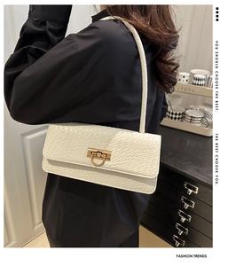 Detail of cream crocodile embossed underarm bag with gold metal clasp on shoulder