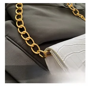Détail macro d'un sac en cuir blanc motif crocodile avec une grosse chaîne en métal doré