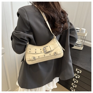 Shoulder bag in beige leather with metal buckle strap detail shown on a model
