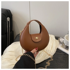 Detail of a brown crescent bag showing smooth faux leather and gold magnetic buckle