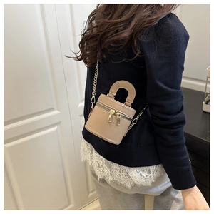 Mini-Zylindertasche in Beige mit goldener Kette in der Seitenansicht am Modell