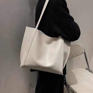 Detail of minimalist cream-colored leather tote bag showing smooth texture and soft drape