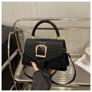 Détail d'un sac noir en cuir avec rabat tissé et boucle dorée en forme de U