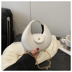 Close-up of white crescent bag featuring a golden round metal clasp and chain strap