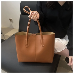 Detail of a brown PU leather tote bag showing the vertical stitching and smooth texture