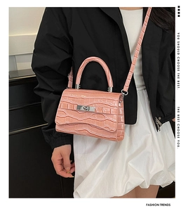 Detailed view of pink croc-embossed handbag with silver twist lock and sturdy handle