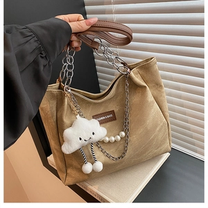 Detail of khaki tote bag with dual chain straps and cute cloud charm on books