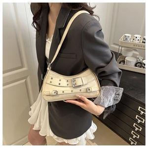 Detail of adjustable silver buckles and eyelets on a cream punk style shoulder bag