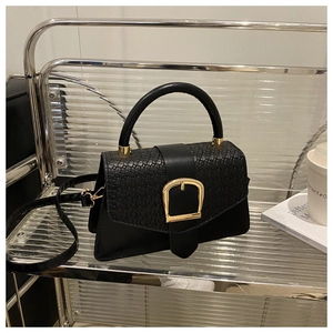 Détail d'un sac à main noir avec texture tressée et boucle demi-cercle en métal doré