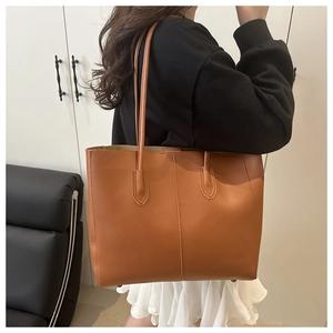 Detailed close-up of brown leather tote bag with elegant stitching and long shoulder strap