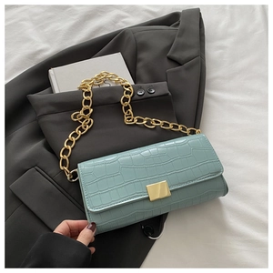 Détail du sac bleu clair à motif crocodile avec chaîne dorée et fermoir carré