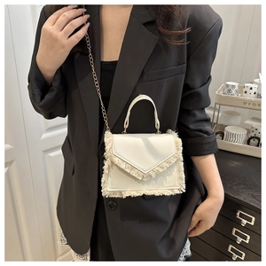 White fringe crossbody bag with gold chain strap shown on a model with black blazer