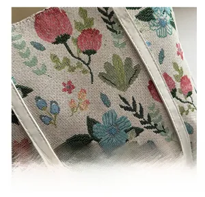 Macro shot of floral jacquard fabric and white leather stitching on a tote bag