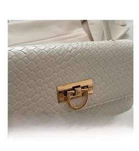Detail of white woven handbag showing intricate texture and golden metal twist lock