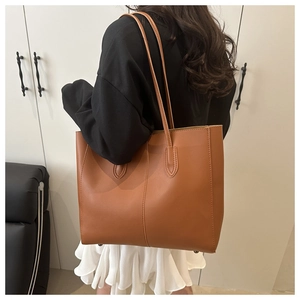Brown leather tote bag shown on a model to demonstrate large capacity and shoulder strap length