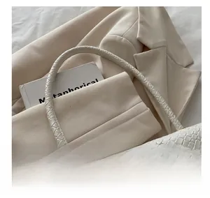 Close-up of white woven leather texture with golden rectangle lock and handle detail