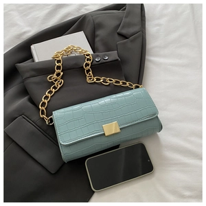 Détail du sac à rabat bleu clair effet croco avec bandoulière chaîne dorée et fermoir