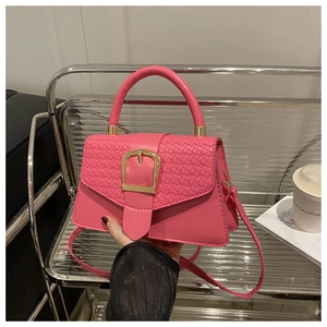 Détail du sac rose vif montrant la texture du rabat tissé et la boucle carrée dorée