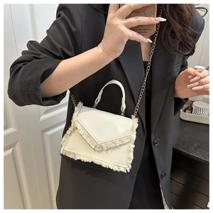 Mirror selfie showing a white crossbody bag with fringe detailing and a gold chain strap