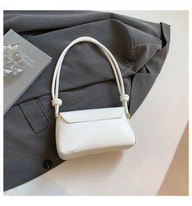 Detail of white rectangle flap bag featuring knotted shoulder strap and gold hardware