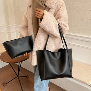 Detail of minimalist black matte leather tote bag with matching zipper pouch and thin straps