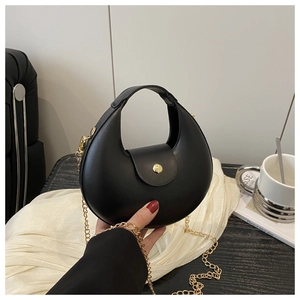 Close-up of black crescent bag featuring golden magnetic buckle and metal chain strap