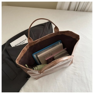 Detail showing high-capacity metallic tote bag interior with books, tablet and umbrella