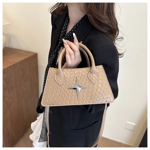 Detail of beige faux leather crossbody bag with crocodile texture and silver star buckle