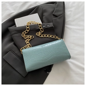 Détail de la texture crocodile bleu clair et de la chaîne dorée épaisse sur le sac