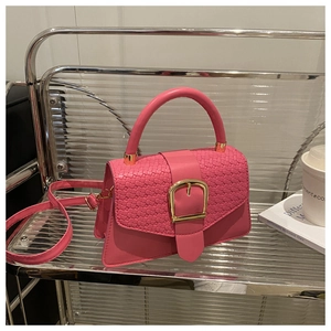 Détail du sac à main rose en cuir tressé avec boucle dorée sur étagère moderne