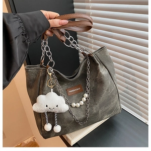 Detail of dark grey tote with metal chains, pearl beads, and white cloud charm accessory