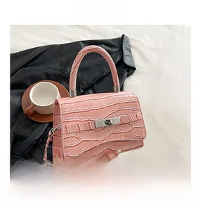 Detailed view of pink croc-embossed handbag with silver twist lock and slim shoulder strap