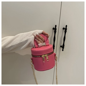 Detail der rosa zylindrischen Beuteltasche mit goldenen Reißverschlüssen und Kette