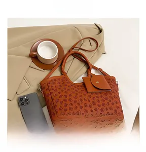 Close-up of embossed floral pattern on a brown leather tote bag with stylish accessories