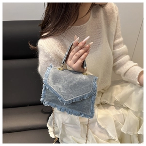 Detail of light blue denim mini bag featuring frayed edges and gold chain strap