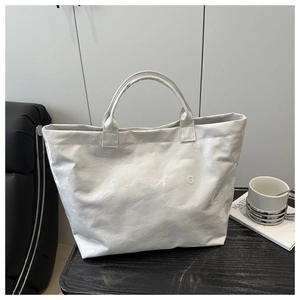 Detailed close-up of white tote bag with DuPont paper texture and embossed TOTE BAG text