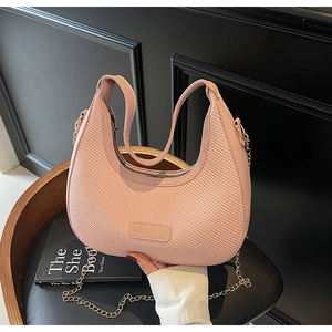 Detailed view of pink woven hobo bag with gold chain strap on a vintage wooden stool
