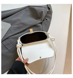 Close-up of a white shoulder bag with a gold metal twist lock and brown fabric lining