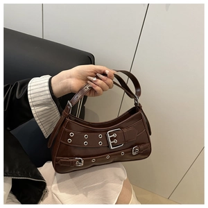 Detail of dark brown crescent bag with metal eyelets and decorative punk style buckles