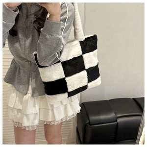 Detail of plush black and white checkerboard tote bag with soft faux fur texture