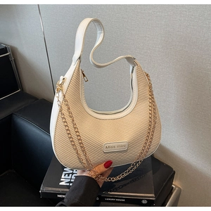 Detail of beige woven half-moon bag with white leather trim and gold chain strap