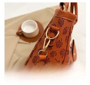 Detailed close-up of golden metal hardware and floral embossed texture on the tote bag