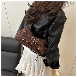 Detail of dark brown faux leather shoulder bag with punk buckles and metal eyelets
