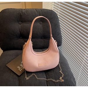 Close-up of pink woven hobo bag with a metal brand plate and stylish gold chain detail