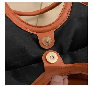 Detail of premium brown leather tote featuring a gold magnetic closure with engraved serial number