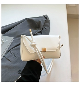 Detail of the white leather bag featuring a gold metal lock and knotted shoulder strap
