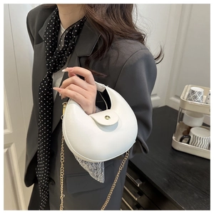 Detailed shot of a white crescent shoulder bag with gold chain and metal buckle closure