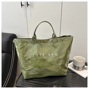 Detail of green waterproof DuPont paper tote bag with white TOTE BAG text on a desk
